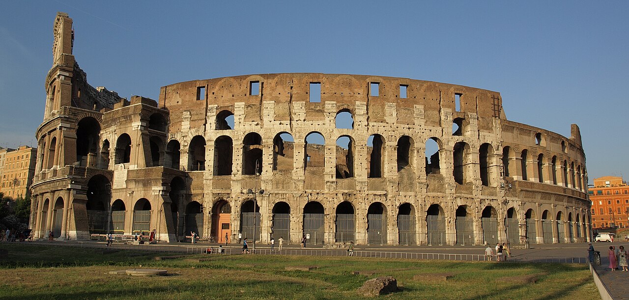 The ancient arches of the Colosseum in Rome in warm evening light.